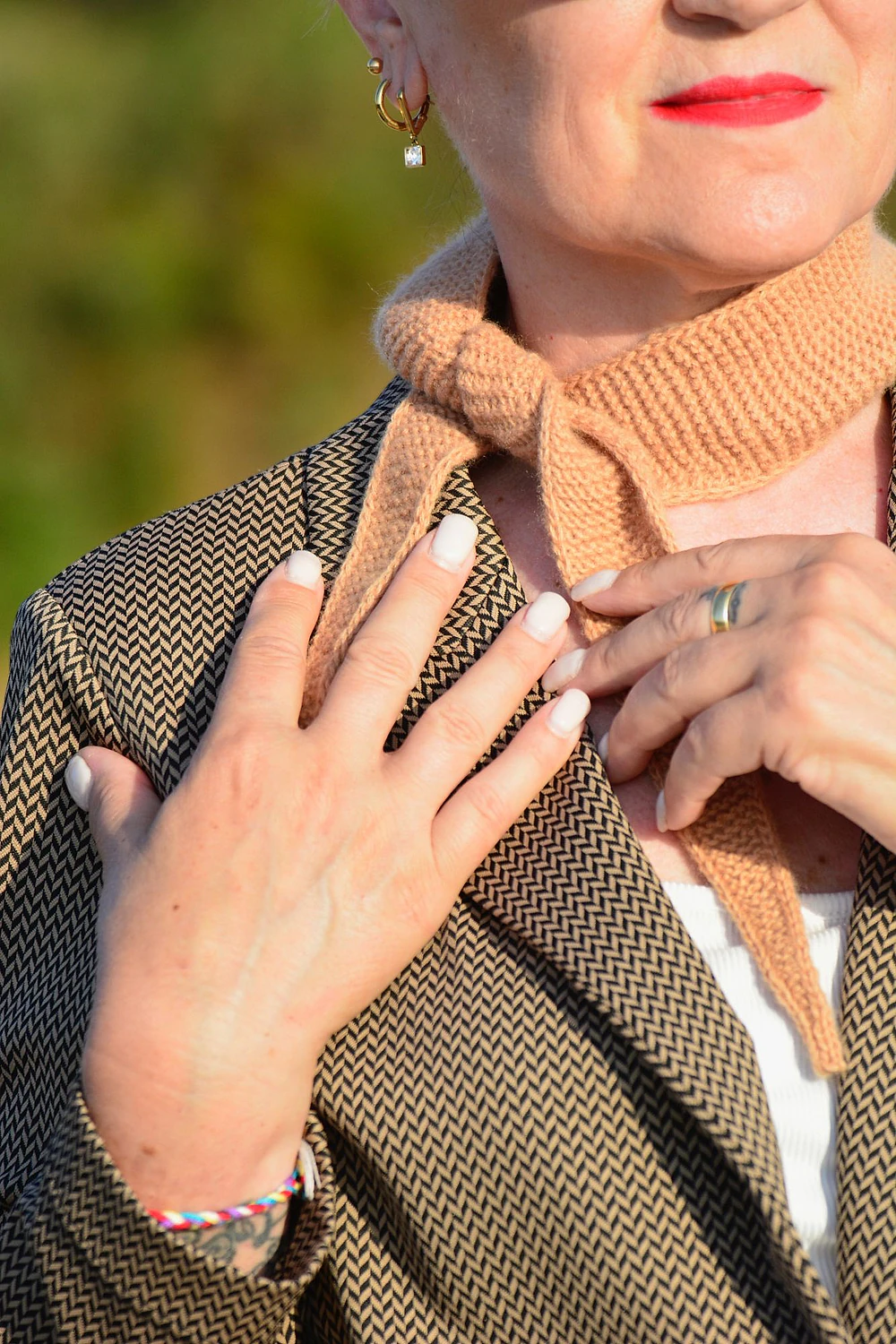 Il foulard annodato al collo, sfiorato dalle mani.